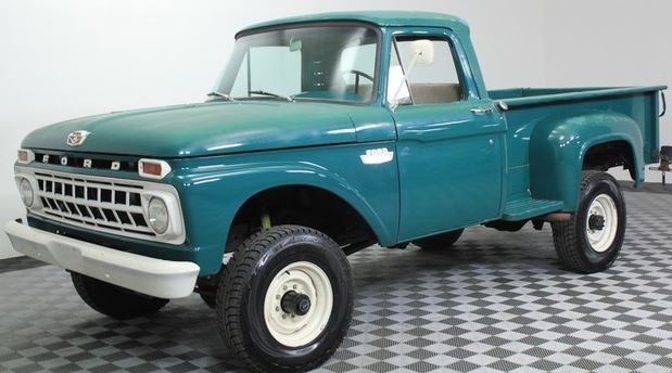 an old green pickup truck is parked in a room with black and white checkered flooring