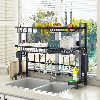 a kitchen sink and dish rack in front of a window with the dishes on it