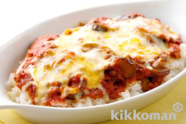 a white bowl filled with rice and meat covered in sauce on top of a yellow napkin