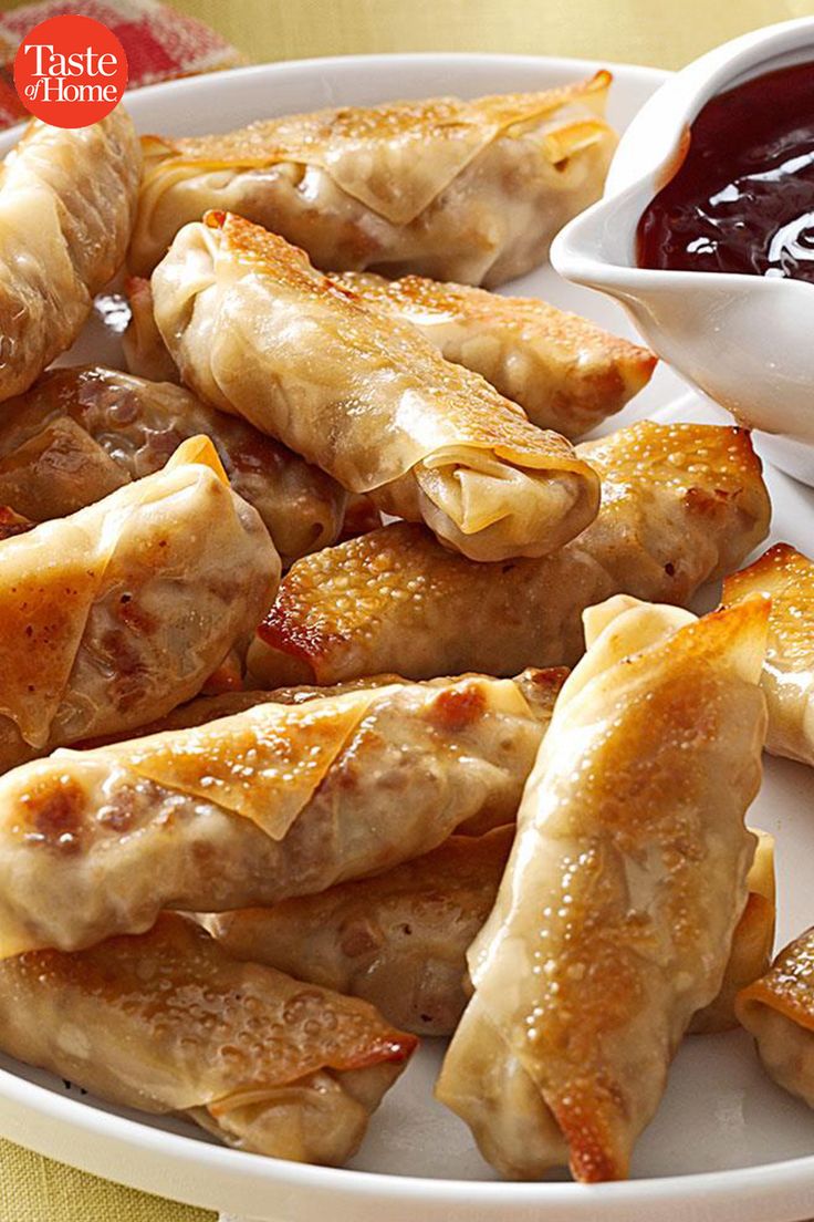 a white plate topped with dumplings next to a bowl of ketchup and dipping sauce