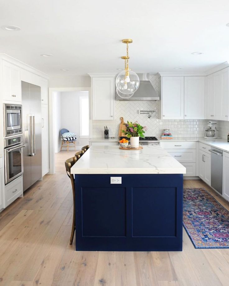 a kitchen with white cabinets and blue island