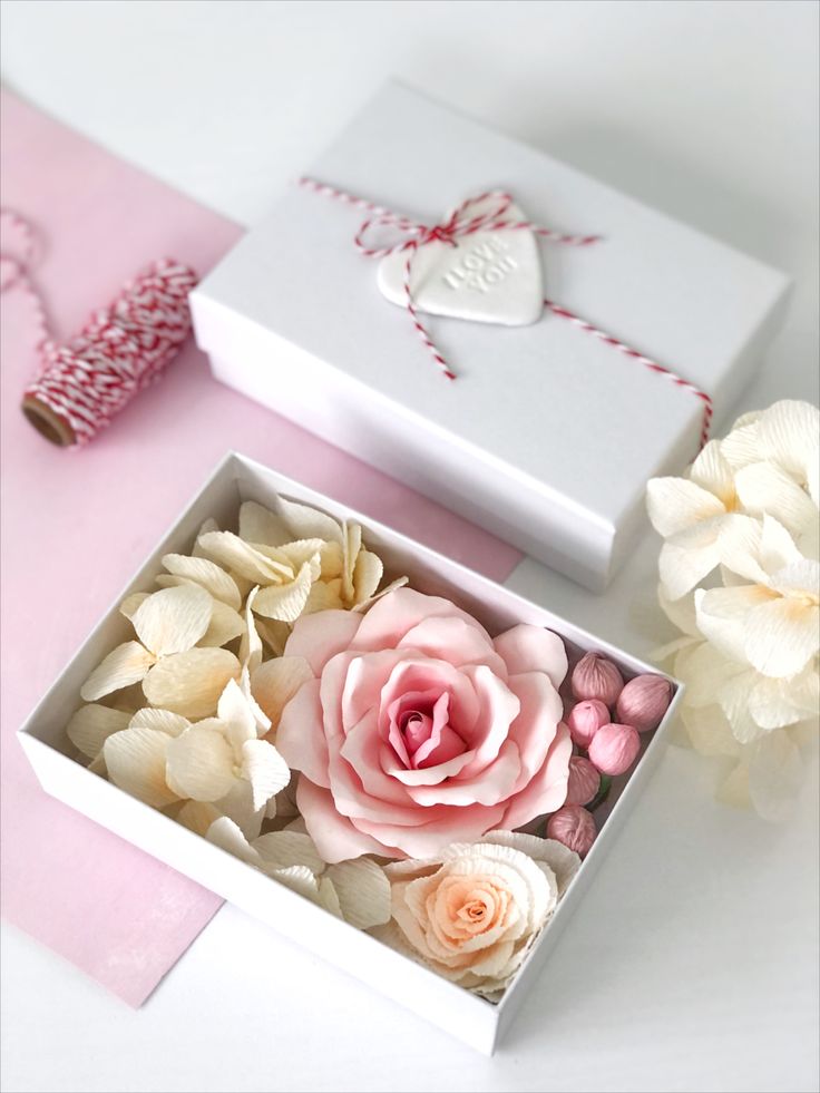 a pink and white box with flowers in it next to a heart shaped ornament