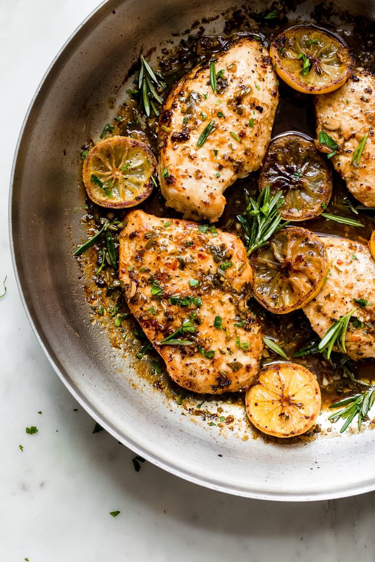 a pan filled with chicken and vegetables on top of a white countertop next to a knife