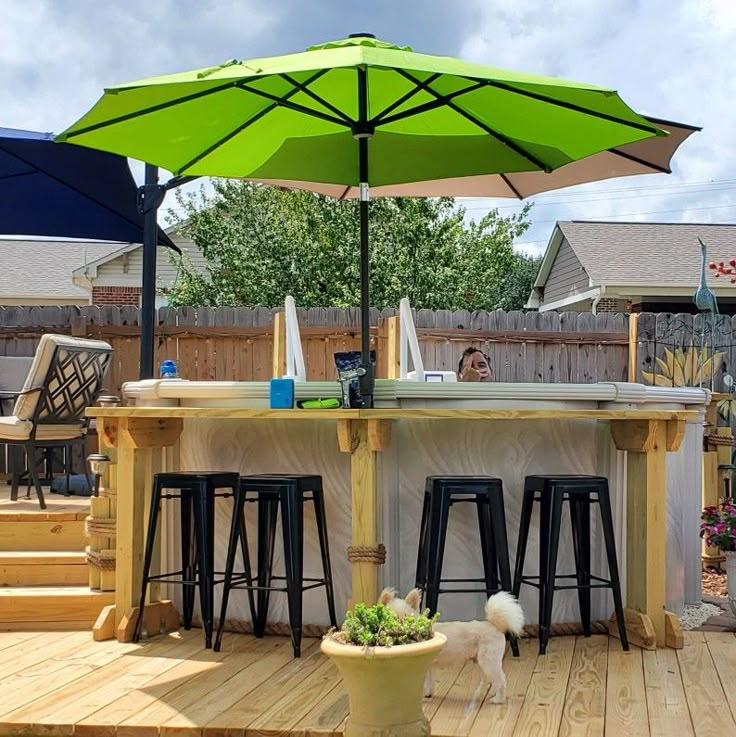 an outdoor bar with stools and umbrella in the back yard on a sunny day