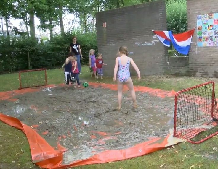 children playing in the mud at an outdoor play area with orange tarps on it