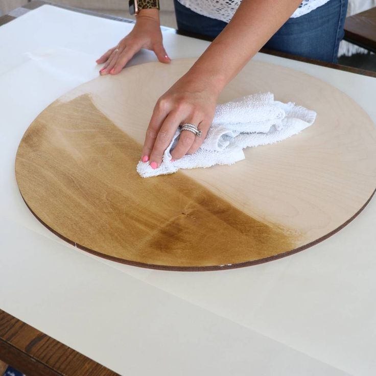 a woman is wiping up some wood with a cloth on top of the wooden table