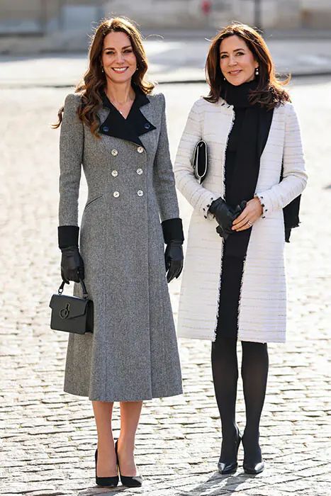 two women standing next to each other on a cobblestone street