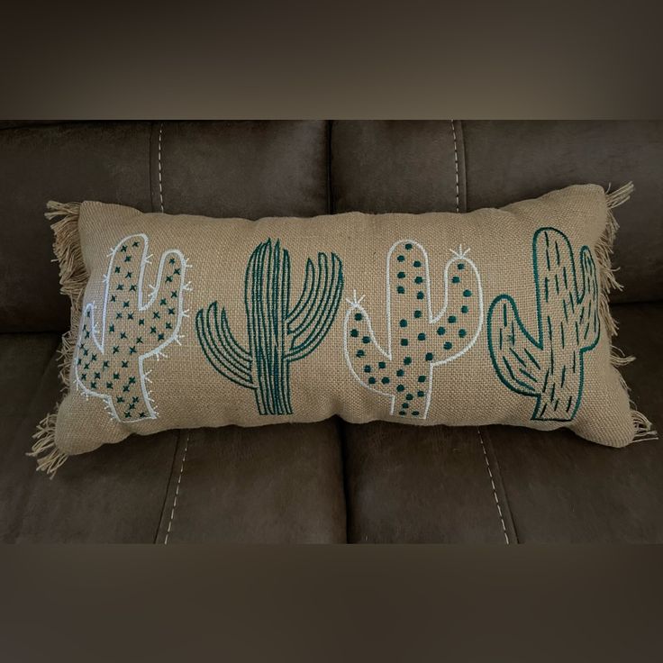 a pillow with cactus designs on it is sitting on a leather couch in the living room