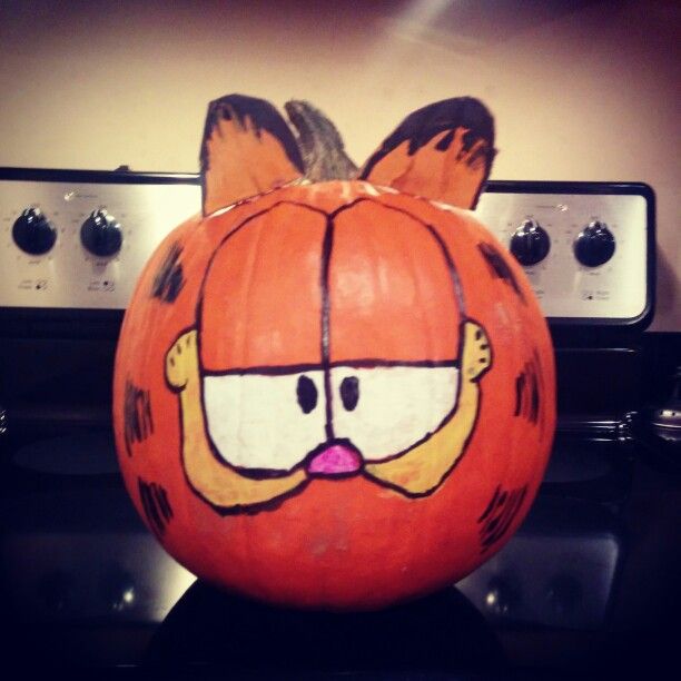 a large pumpkin with an angry face drawn on it's head and eyes, sitting in front of a stove