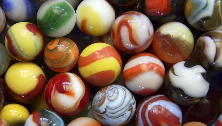 many different colored marbles are shown in this close up photo, including one with an orange stripe