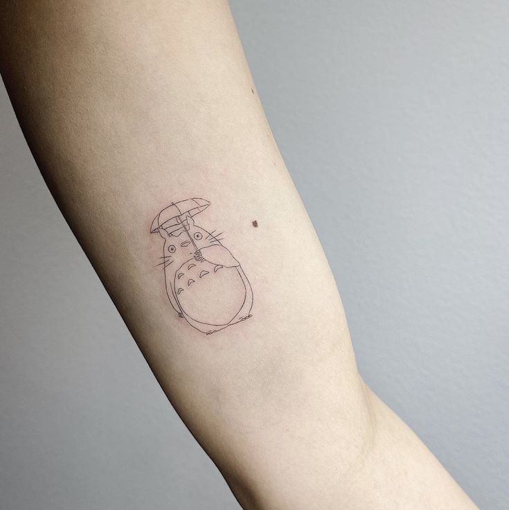 a person's arm with a small tattoo of a totoro on it