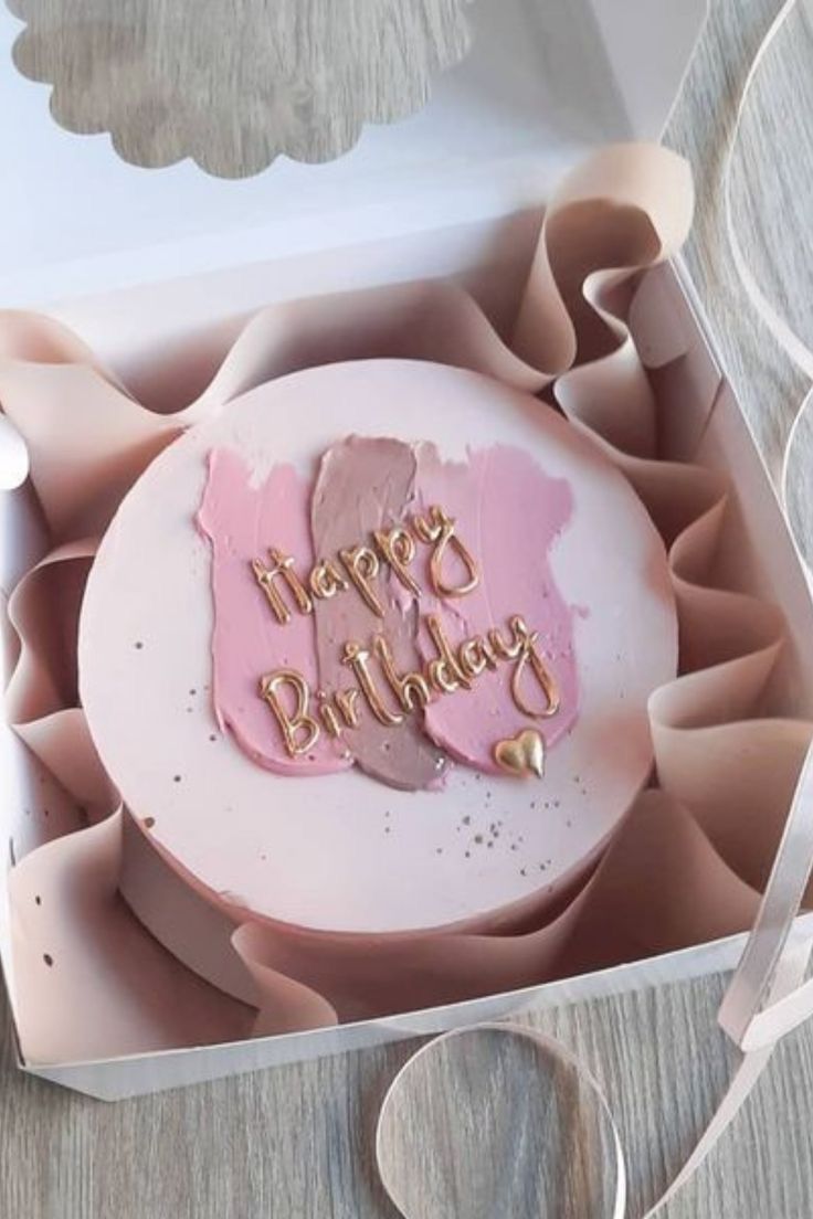 a pink birthday cake in a box on a table