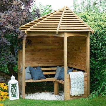 a wooden gazebo sitting in the middle of a lush green field