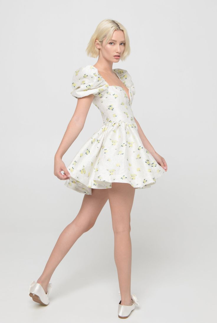 A kind reminder that all sale items cannot be returned for a refund or exchange. These items are FINAL SALE. The Enchanted Rose Mini is a playful dress made for twirling and overlooking the chateau gardens. Its regal elegance comes from the dainty floral jacquard depicted. Best paired with lace gloves. Jacquard 100% Polyester U-wire neckline Elasticated puff sleeves Fit and flare style Deep v waistline Voluminous skirt Back smocked bodice Soft cotton poly lining Hand wash, Dry clean Product Meas Whimsical Party Dress With Fitted Bodice, Whimsical Mini Length Party Dresses, Whimsical Short Sleeve Dresses For Summer, Whimsical Short Sleeve Summer Dresses, Flirty Puff Sleeve Dresses For Garden Party, Whimsical Summer Mini Dress, Spring Fitted Bubble Dress With Ruffles, Fitted Bubble Dress For Dress Down Spring Occasions, Flirty Fitted Bodice Dress For Garden Party