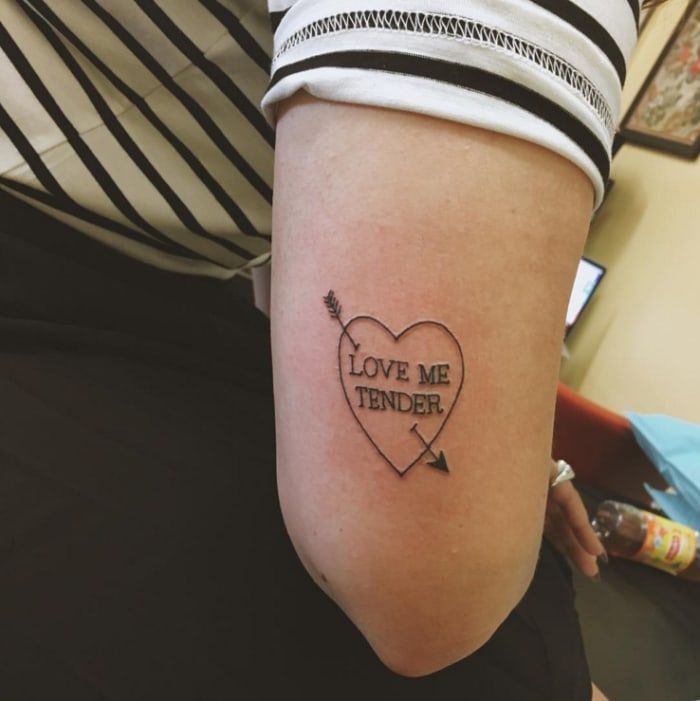 a woman's arm with a tattoo that says love me tender and an arrow