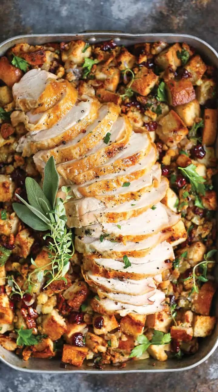 a pan filled with chicken and stuffing on top of a table next to utensils