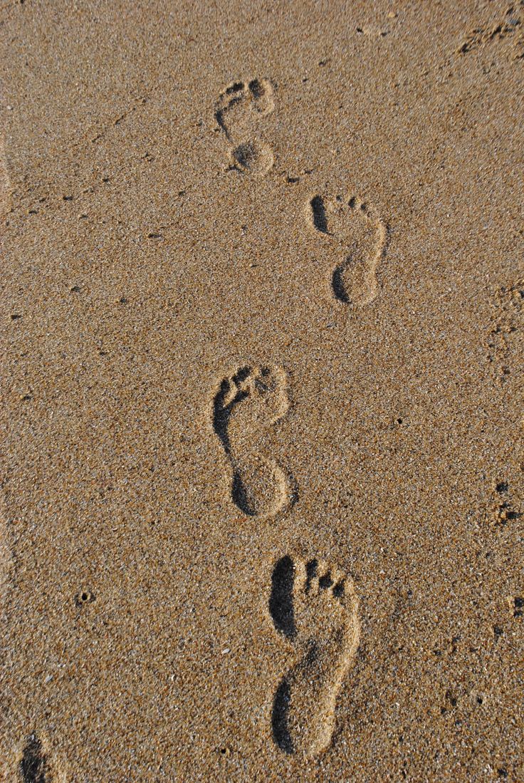 two footprints in the sand near one another