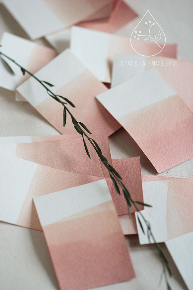 some pink and white papers are laying on the table with green stems sticking out of them