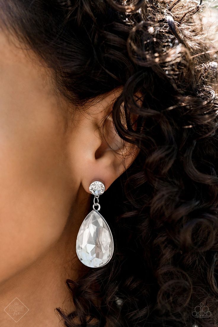 a close up of a woman's face wearing large earrings with tears on them