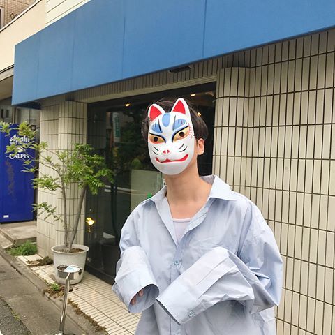 a person with a cat mask on standing in front of a building