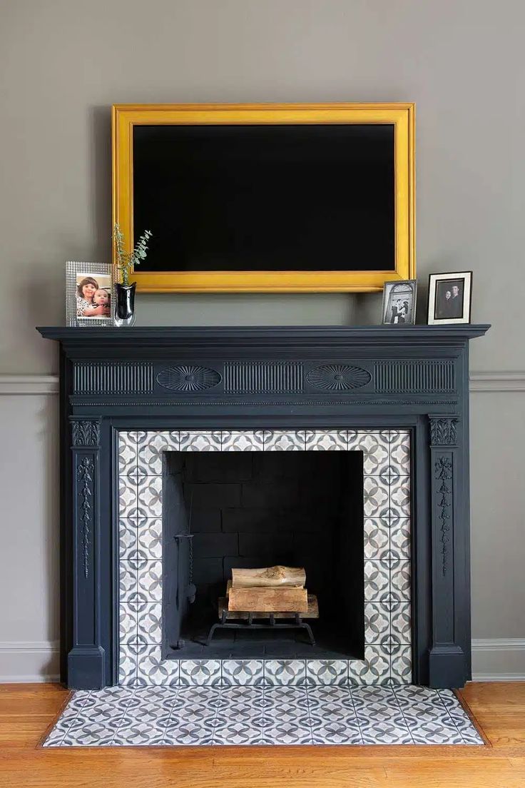 a fireplace with a tv above it and pictures on the mantel top, in front of a gray wall