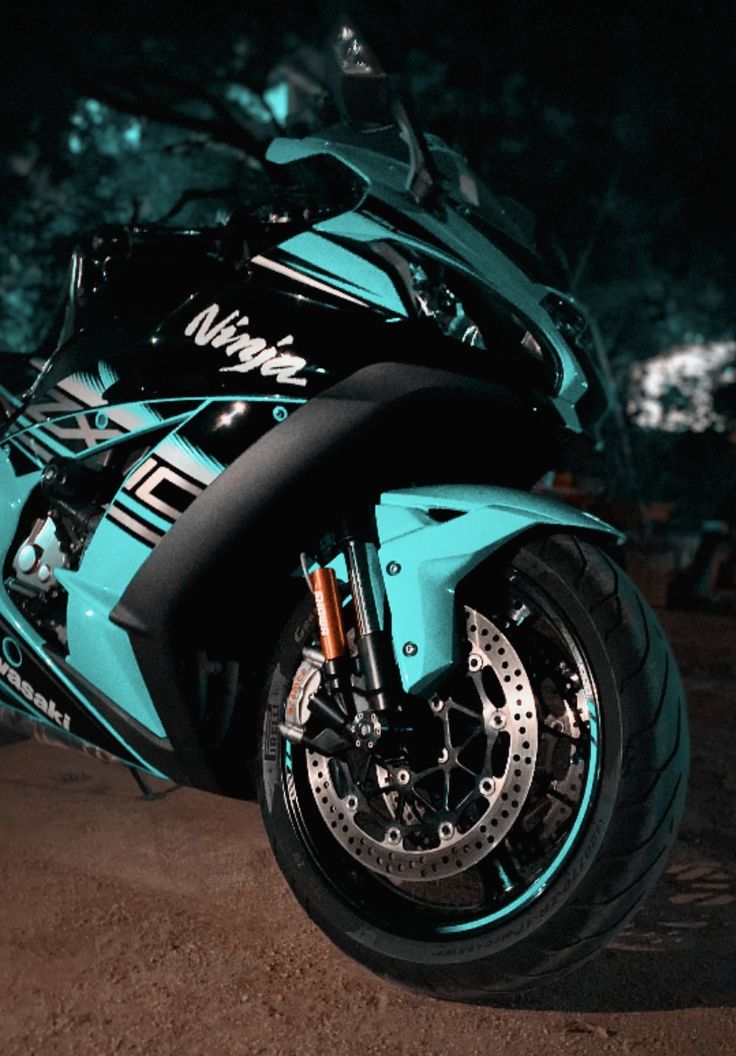 a blue motorcycle parked on the side of a road at night with trees in the background