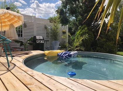 an empty swimming pool with umbrellas and lounge chairs in the back yard on a sunny day