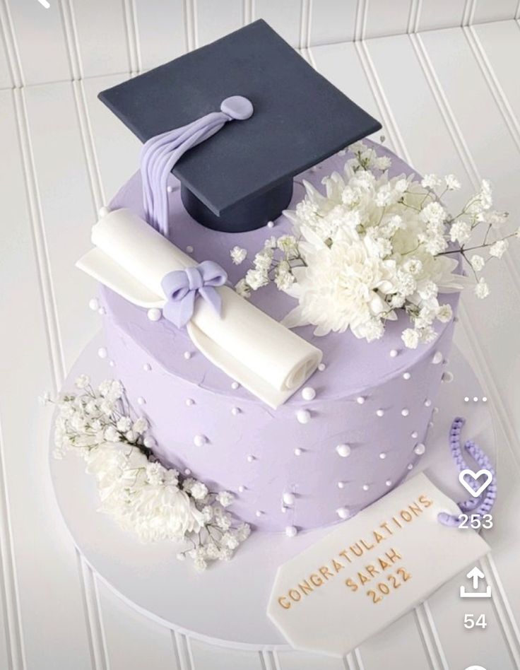 a purple cake with white flowers and a graduation cap on top