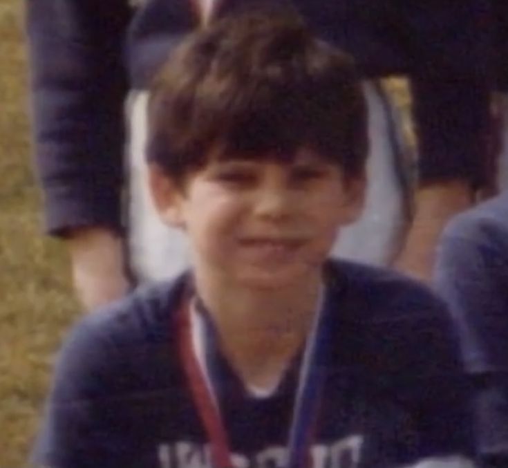 a young boy is posing for a photo with his medal around his neck and hands on his chest