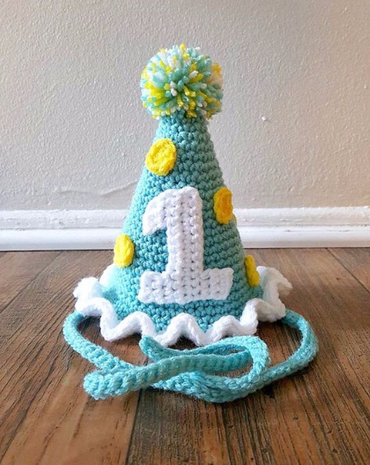 a crocheted birthday hat with the number one on it sitting on top of a wooden floor