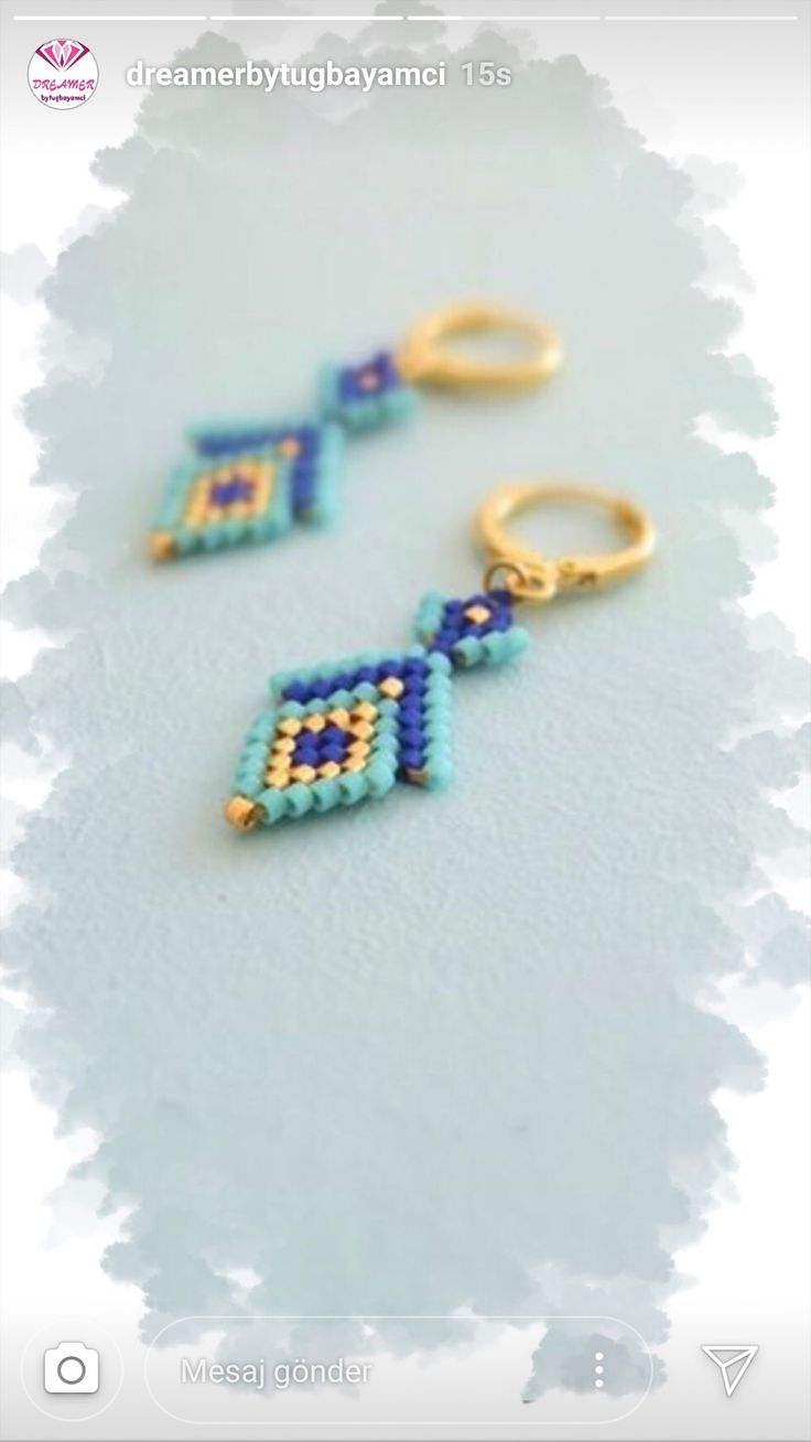 two small beaded earrings are shown on a white surface with the word dream written in gold