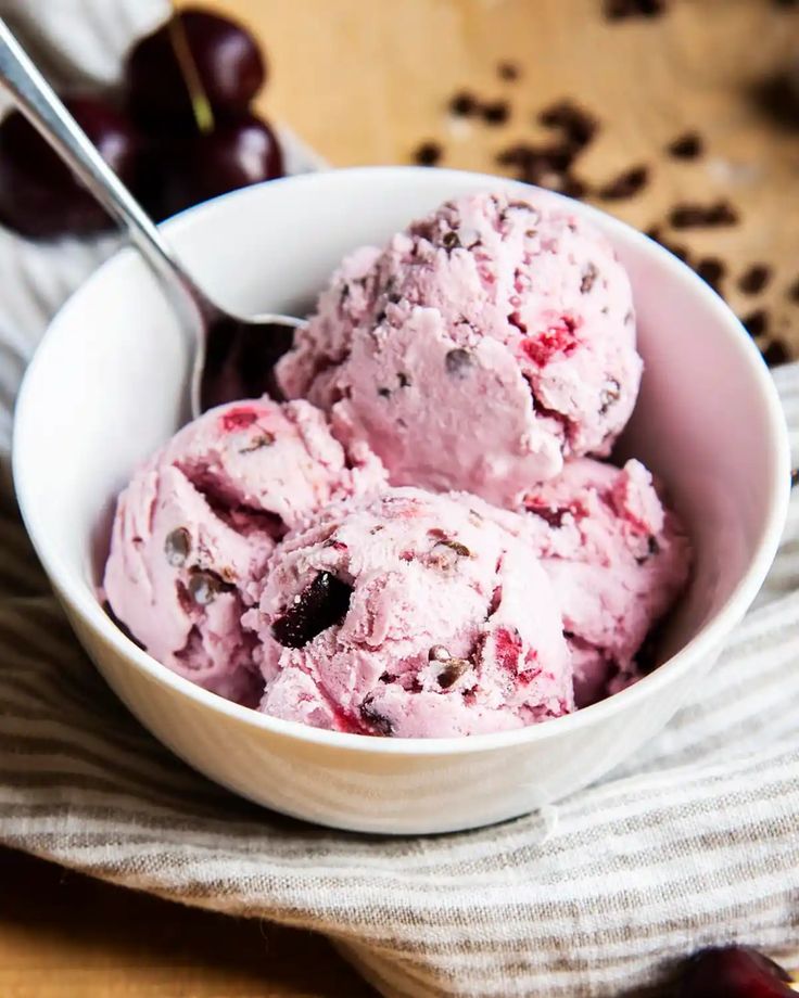 a white bowl filled with ice cream and cherries