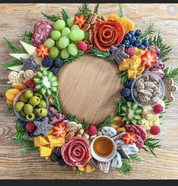 a wreath made out of fruits and vegetables on top of a wooden table next to a cup of coffee