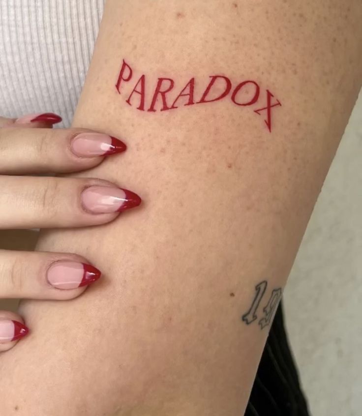 a woman's arm with the word paradox tattooed on her left side