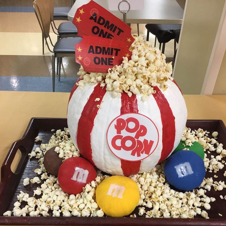 a tray with popcorn and balls on it in the shape of a pumpkin that says pop corn