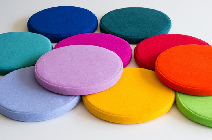 several different colored round cushions sitting on top of each other in the middle of a white surface