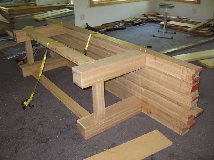 a wooden bench being constructed in a room with other pieces of wood on the floor