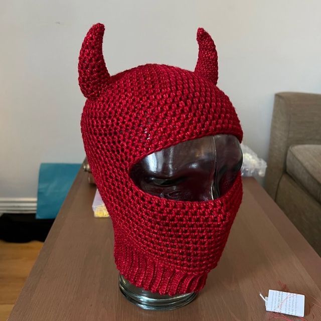 a red knitted hat with horns is on top of a table in front of a couch