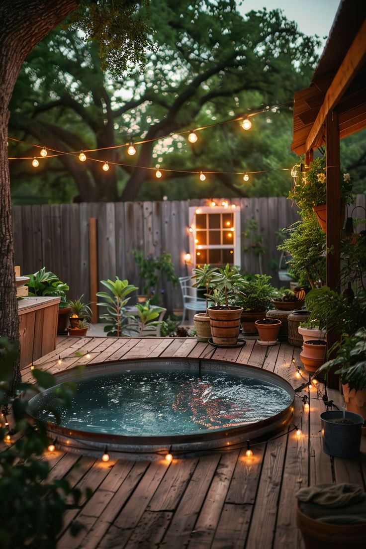 an outdoor hot tub surrounded by potted plants and trees with lights strung over it