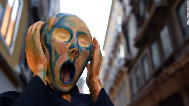 a man with his mouth open and painted like a demon in front of a building