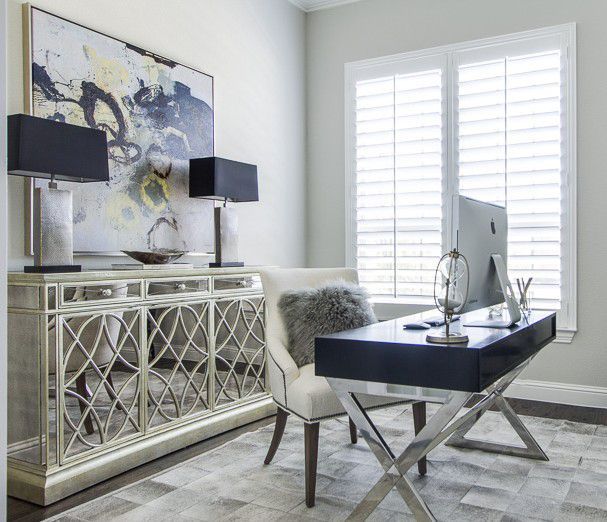 a living room with a desk and chair next to a large painting on the wall