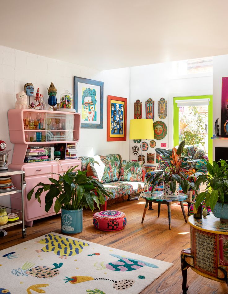 a living room filled with lots of furniture and plants on top of wooden flooring