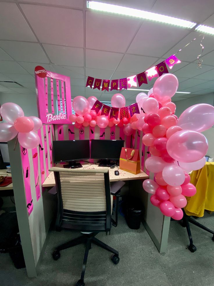 an office cubicle decorated with pink balloons and streamers for a birthday party or baby shower