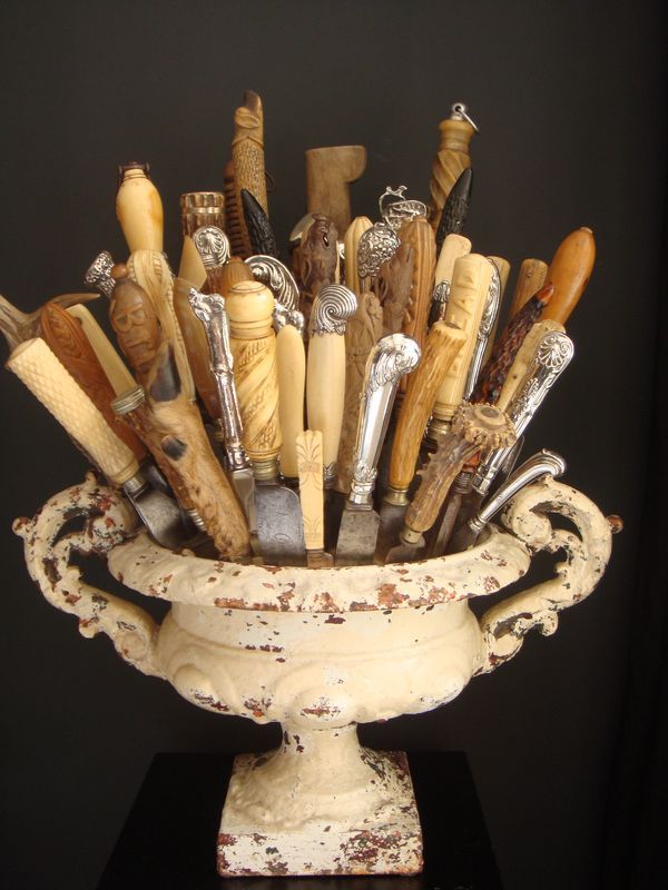 a white vase filled with lots of different types of knives in it's center