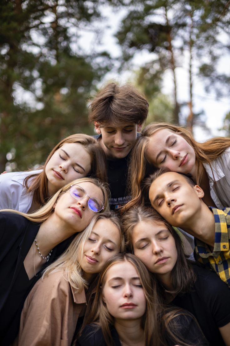 a group of young people standing next to each other with their eyes closed and looking at the camera