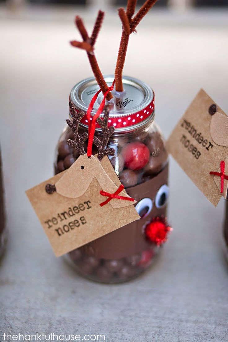 two mason jars filled with chocolate covered candies and reindeer noses, tied with twine