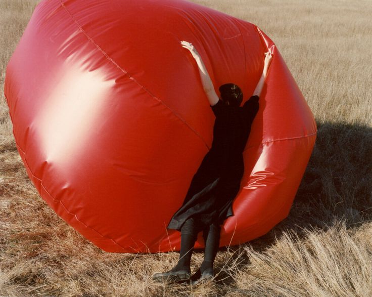 a woman standing in front of a large red balloon