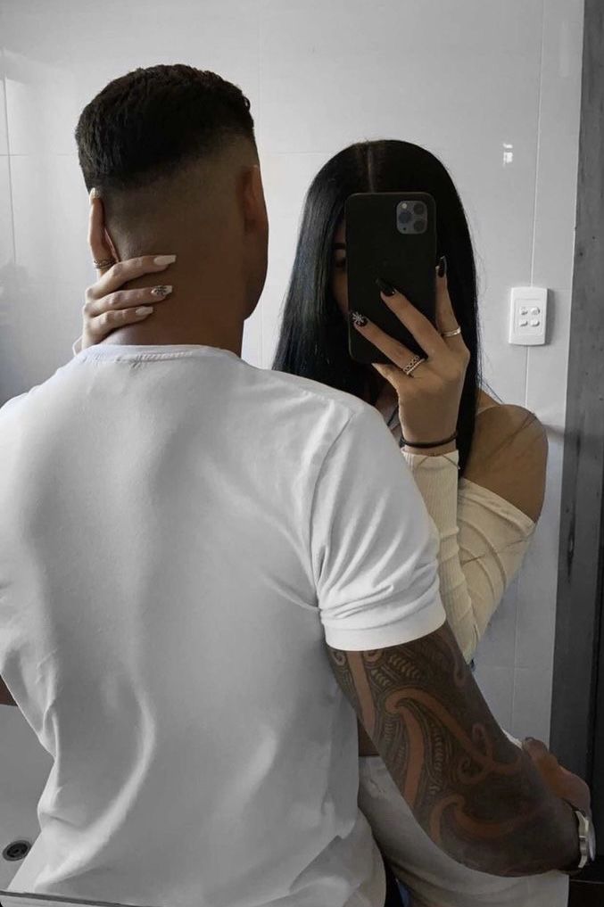 a man taking a selfie in front of a mirror with his arm around a woman's neck