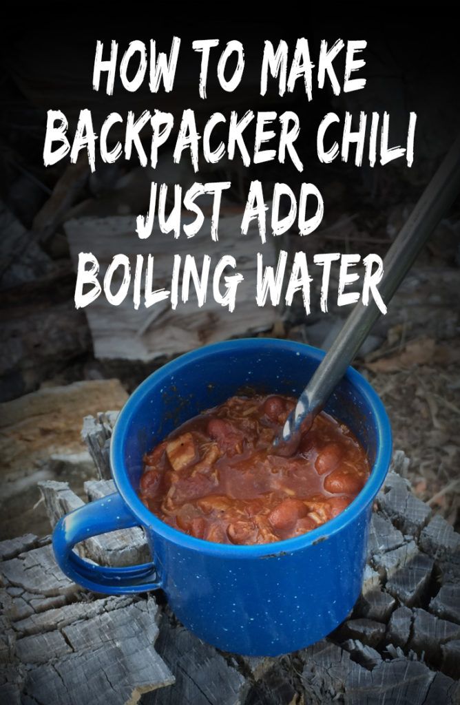 a blue pot filled with chili sitting on top of a pile of wood