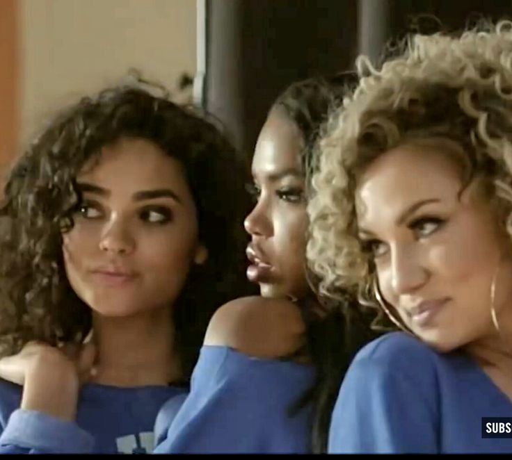 three beautiful women with curly hair posing for the camera